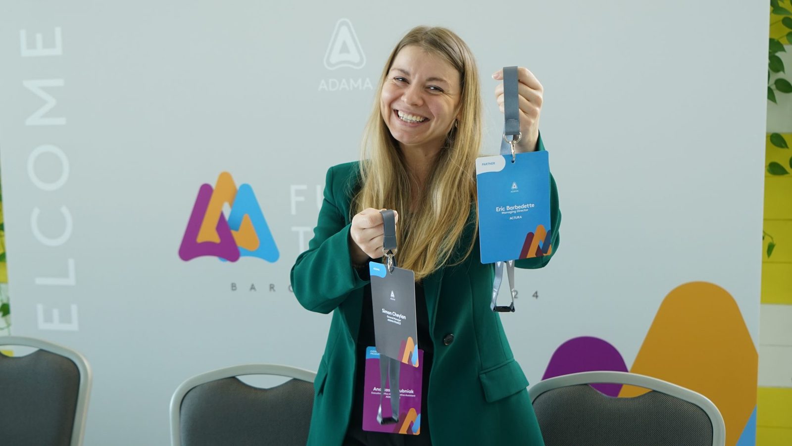 Further Together, Barcelona 2024: participante sorrindo com a credencial, diante do painel de boas-vindas