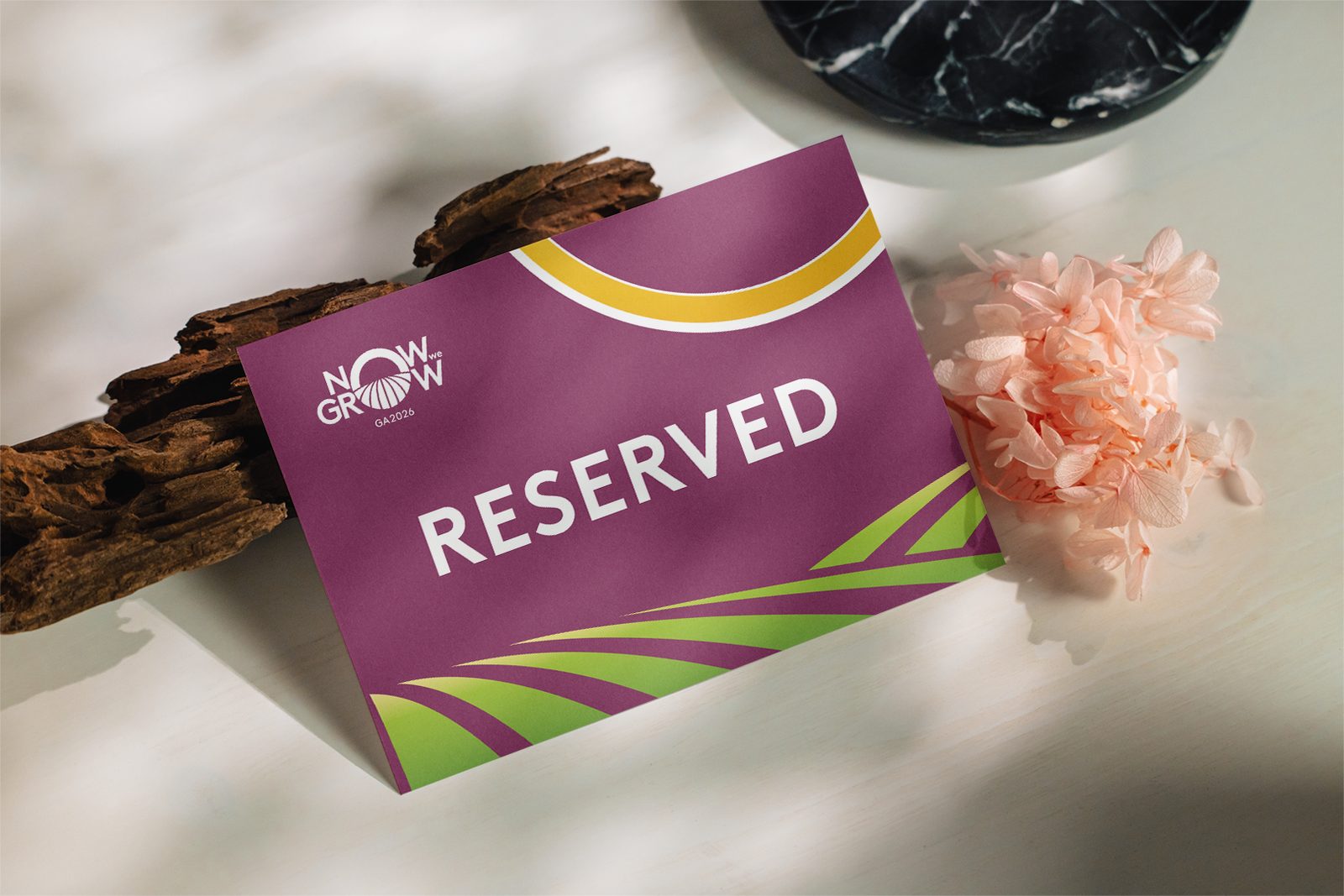 Now We Grow, Budapeste 2026: placa “Reserved” sobre madeira e flores, com a identidade do evento