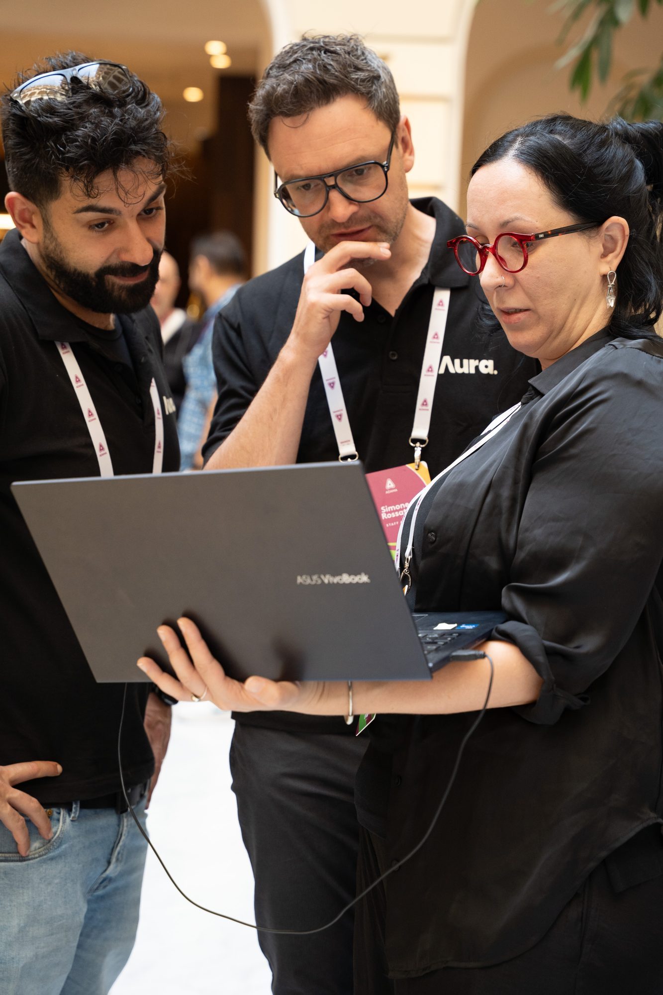 Now We Grow, Budapeste 2026: equipe da Aura conferindo um notebook durante a montagem