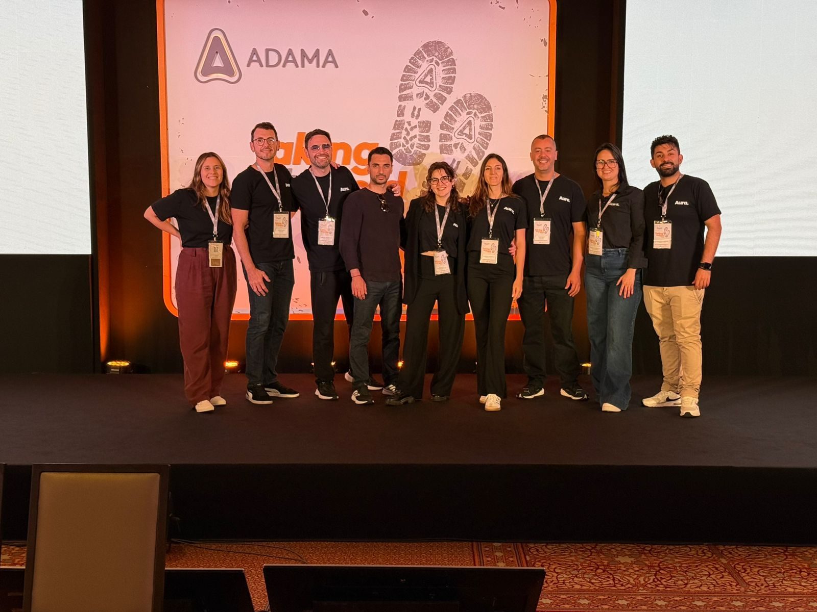 Take The Field, Pafos 2025: equipe posando no palco, diante da tela do evento