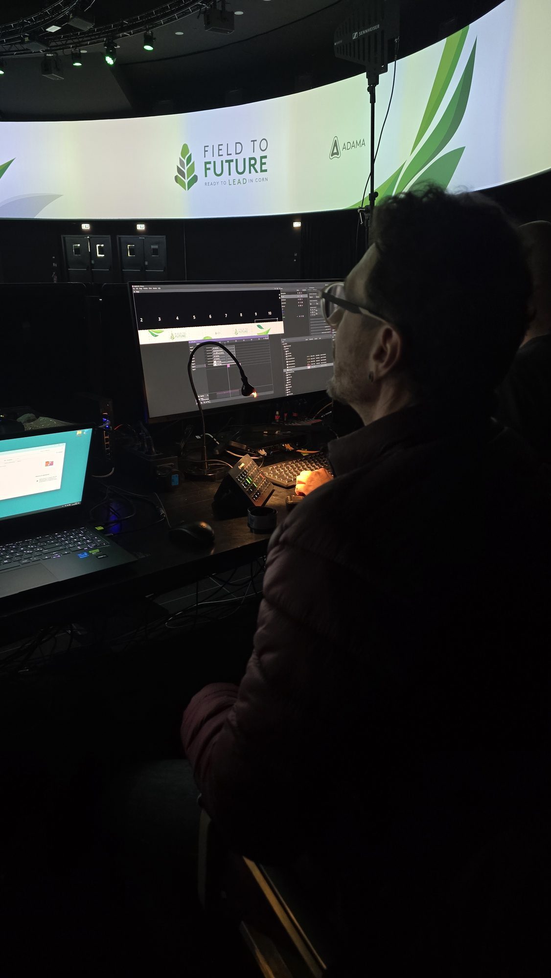 Field to Future, Milão 2026: operador na cabine de controle, com a tela 360° ao fundo