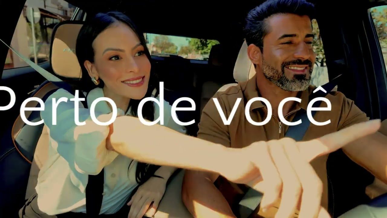 Casal dentro do carro, com a frase “Perto de você”