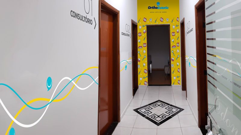 Corredor da clínica com adesivos coloridos e a marca