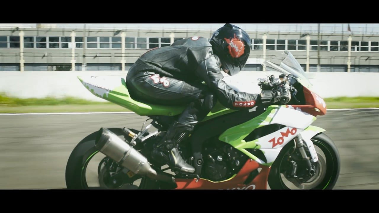 Motociclista em moto verde com a marca Zomo