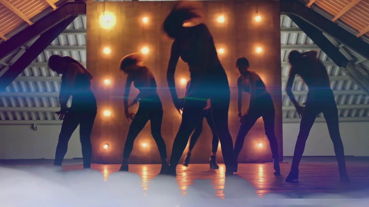 Bailarinos em silhueta, com luzes e fumaça no palco